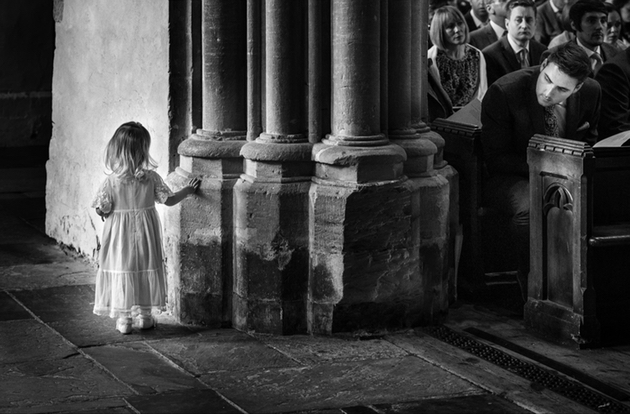 Little girl in church behind a pillar with her father watching on