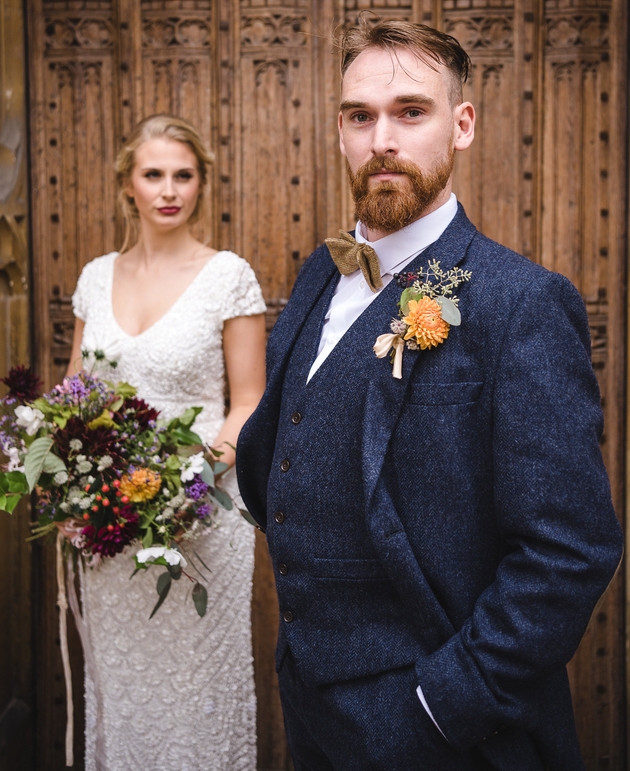Groom stands in front of his bride in a blue three-piece suit from The Cotswold Tailor