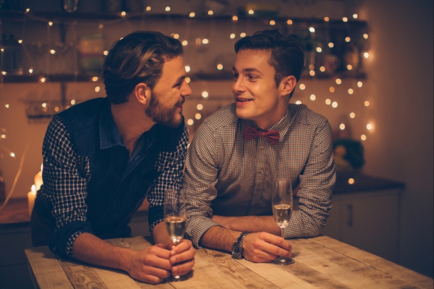 couple drink champagne in a kitchen lit up by fairylights