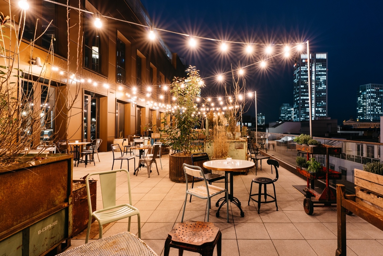 hotel roof terrace with bar and fairy-lights and chairs at night 
