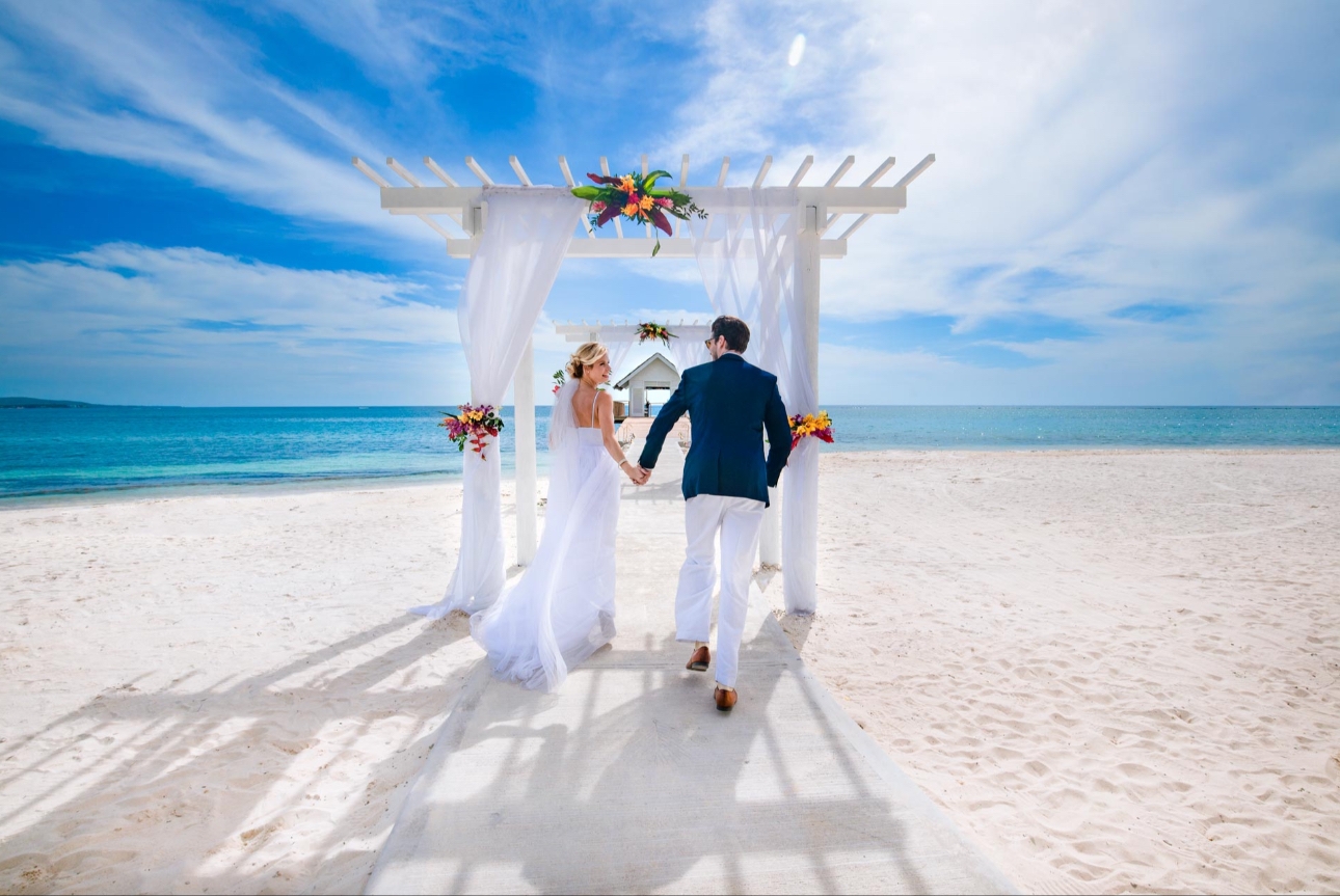 Couple approach white pergola on beach by the sea