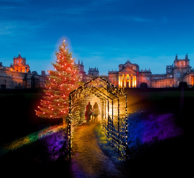 Couple walk through an illuminated arch at Blenheim Palace