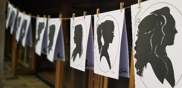 Paper silhouettes hang on string