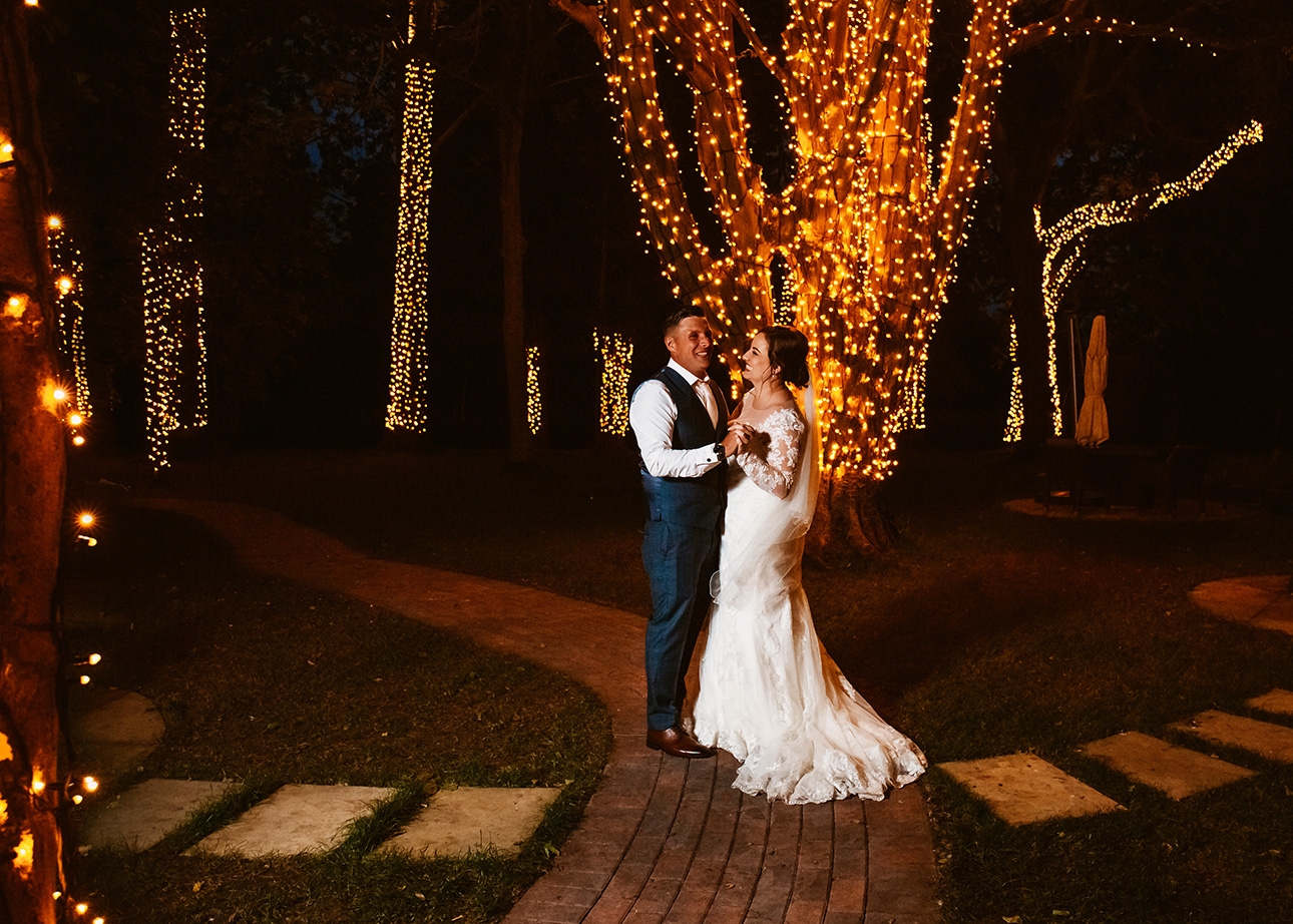 Couple pose in lit up  garden
