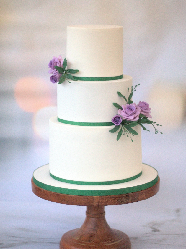 simple three-tired layer white cake with green ribbon and flowers