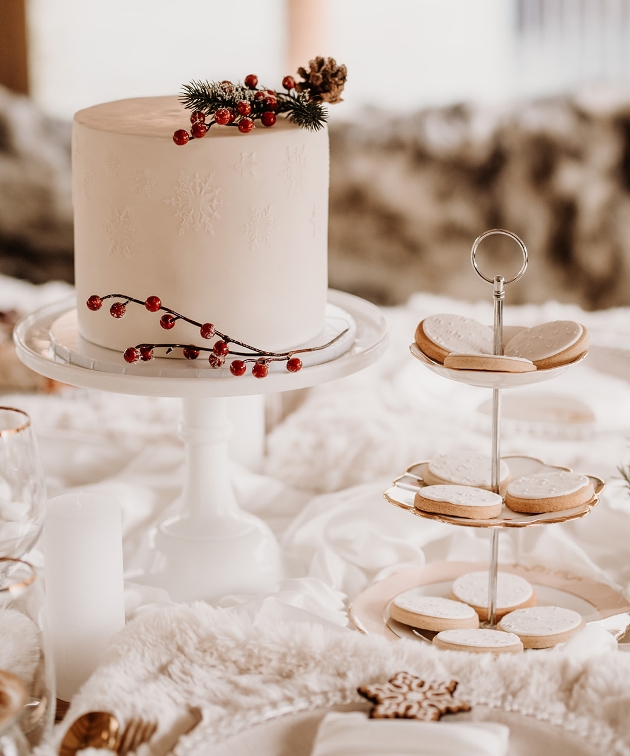 small one tier white cake with flower stood next to a cake display of cookies