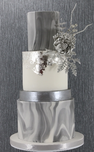 three tiered grey cake with white and marbled layers and silver flowers on top