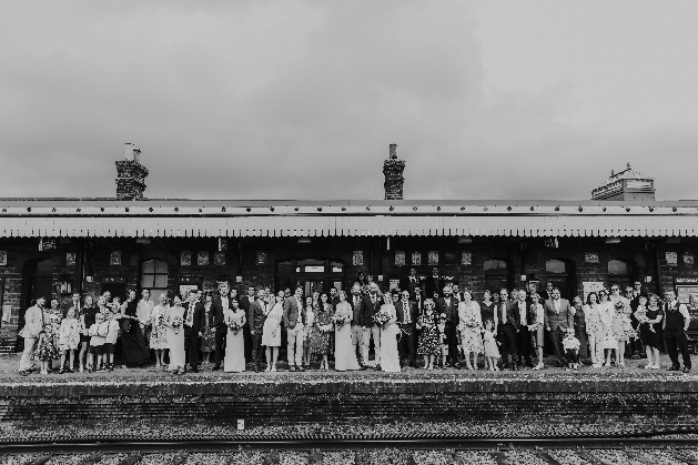 Whole wedding party pose on train platform