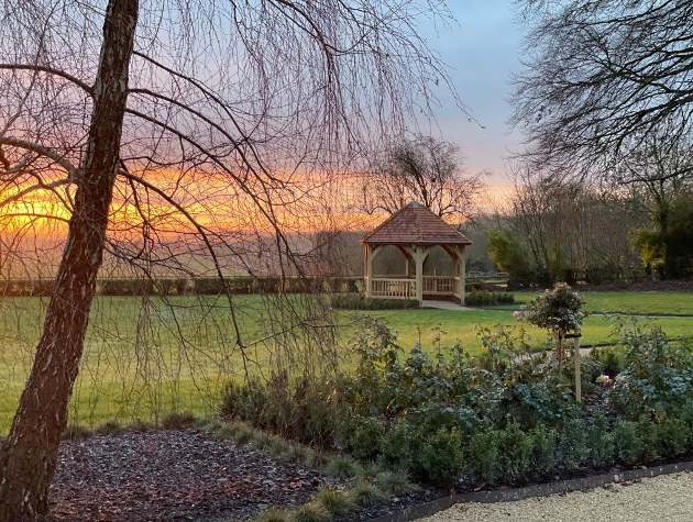 wooden gazebo at the end of gardens with hillside views