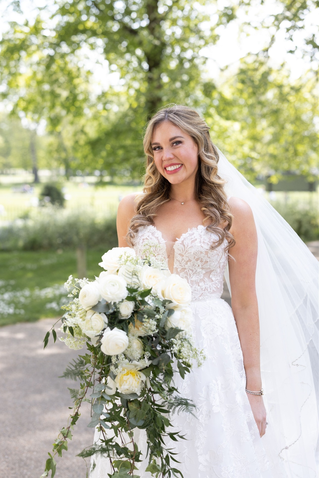 bride with big smile in wedding dress holding white and green bouquet