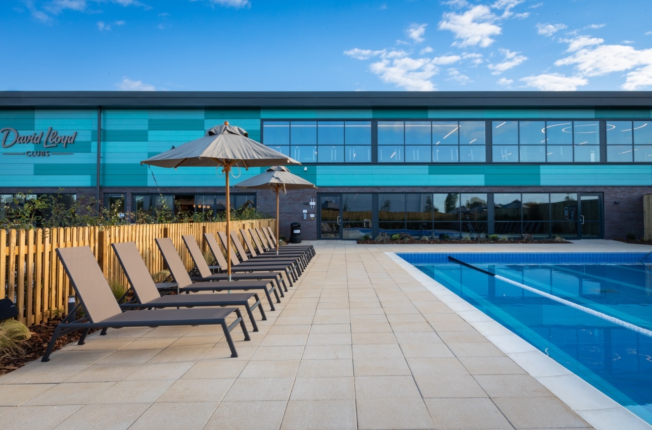 Outdoor pool with sunloungers outside David Lloyd Health Club in Bicester