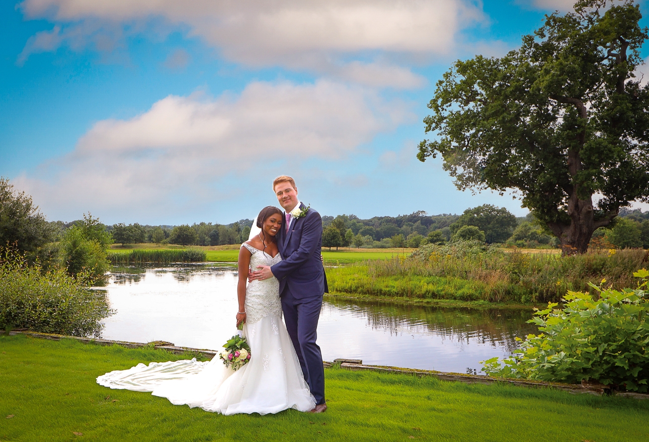 couple in front of lake in wedding clothes