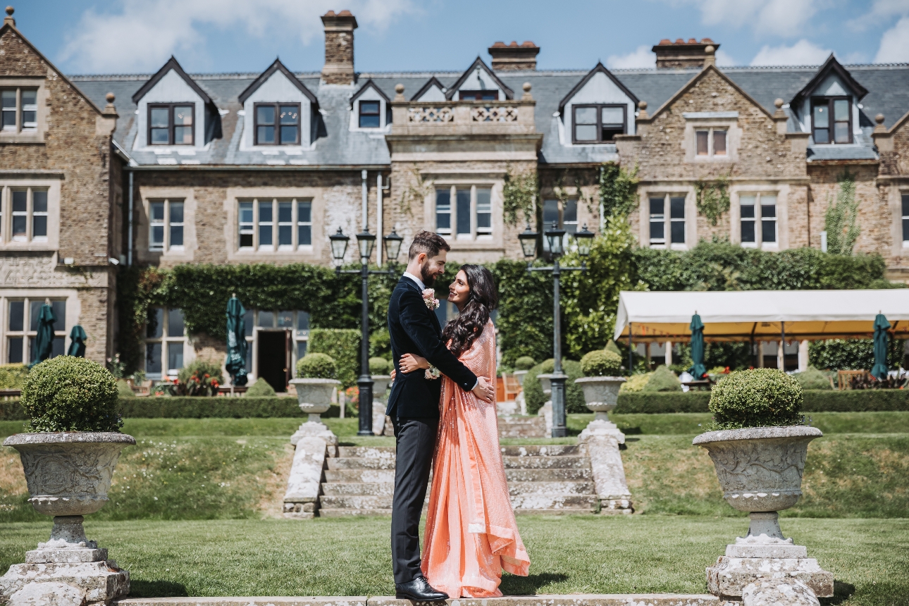 couple in wedding attire standing in front of historic mansion house