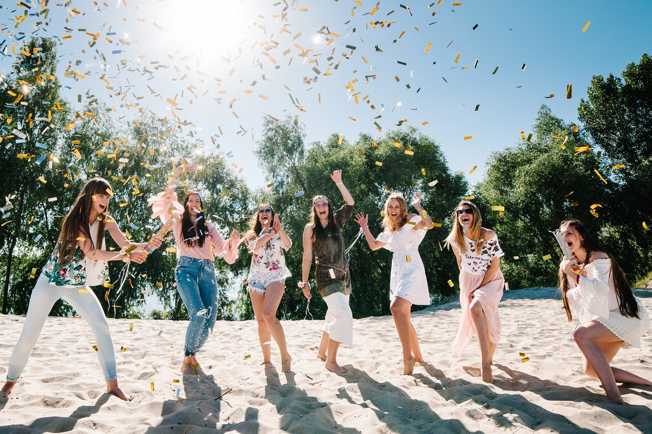 group of women on a sunny beach celebrating with a confetti cannon