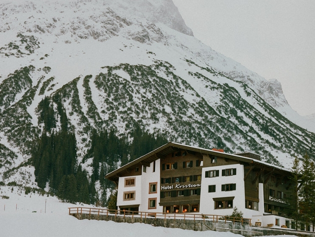 A white and black building sitting at the bottom of a snow-covered mountain