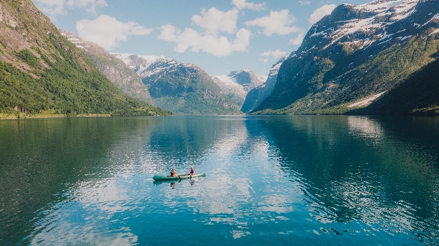A large body of water in between two mountains with a small boat in the middle