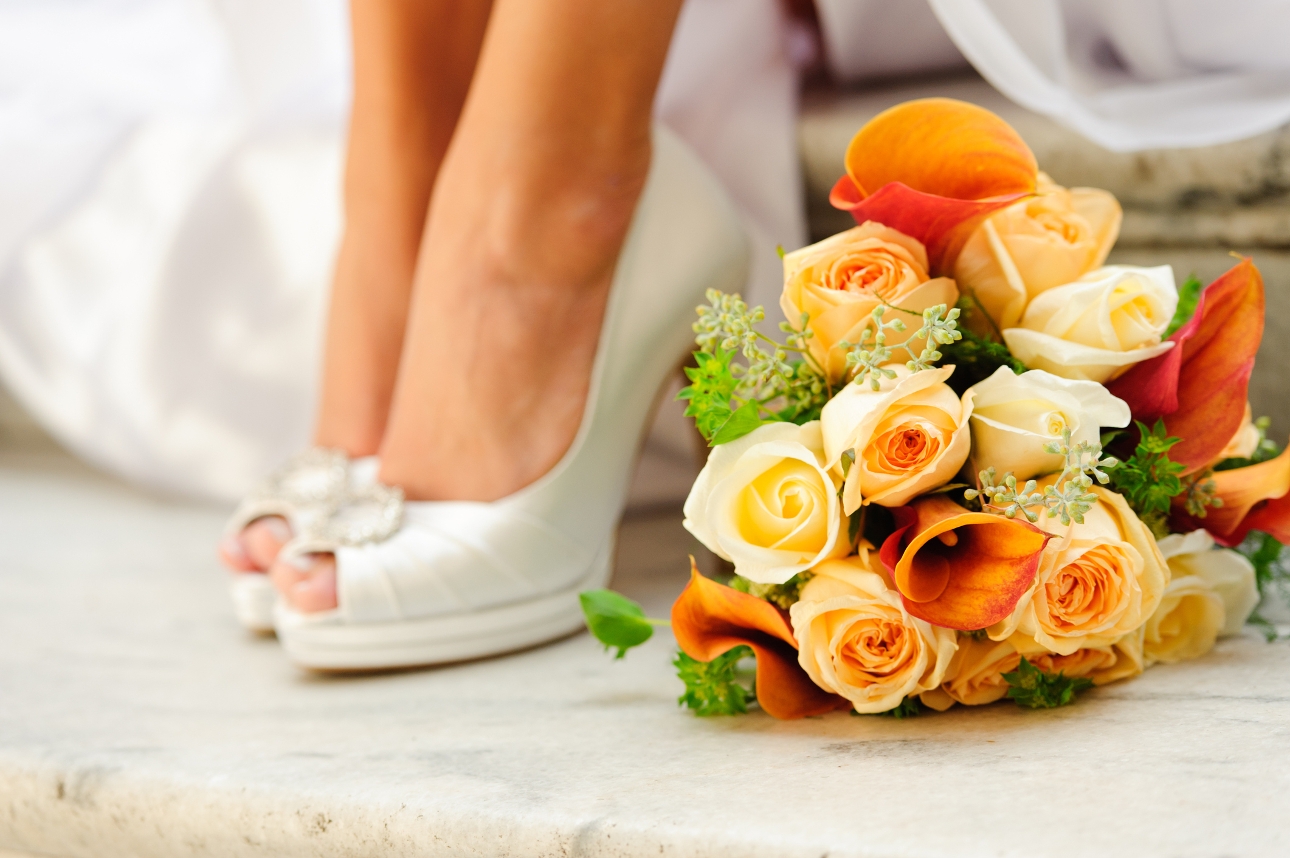 pair of wedding shoes next to an orange bouquet 