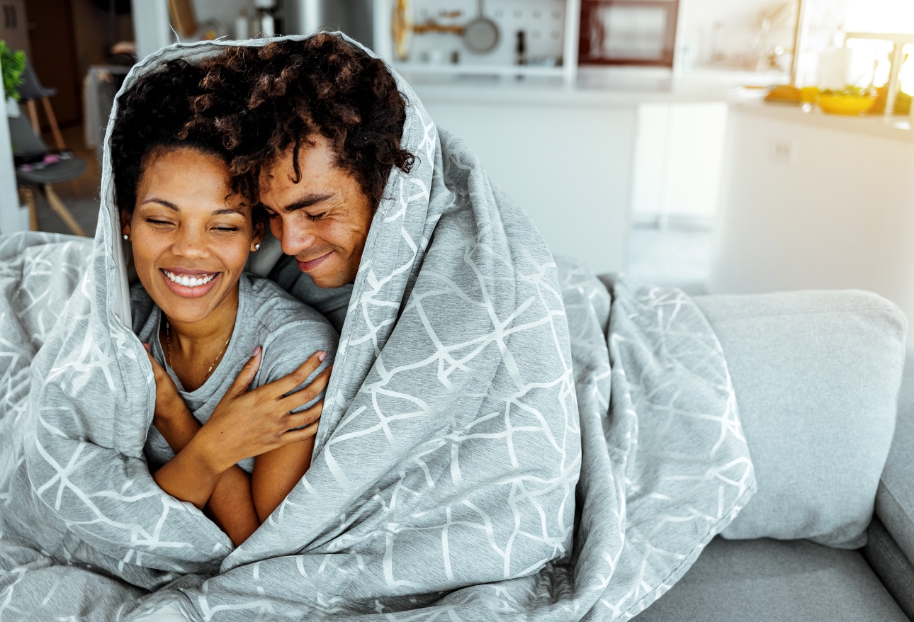 couple cuddle up under blanket