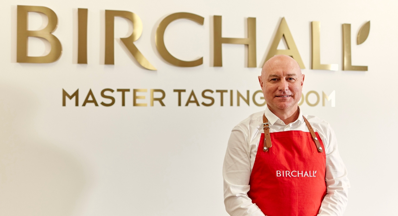 Man stood in front of large gold sign