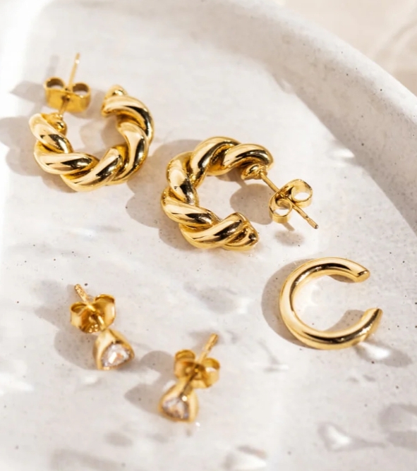 gold jewellery pictured on a stone textured dish